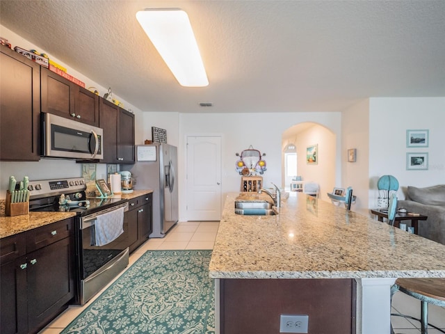 kitchen featuring stainless steel appliances, a breakfast bar, an island with sink, and a sink