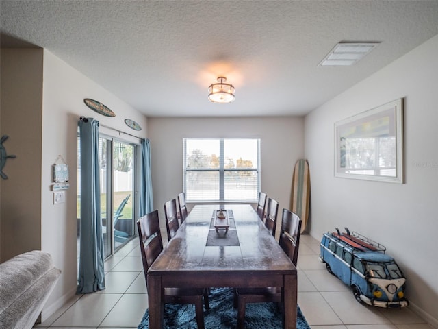 dining area with visible vents, a textured ceiling, baseboards, and light tile patterned floors