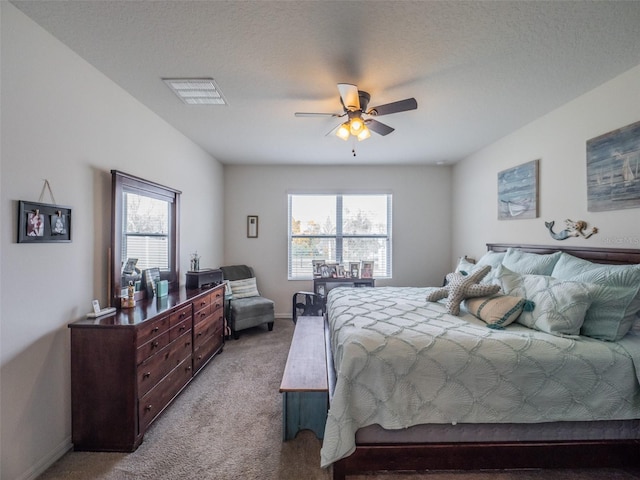 bedroom featuring light carpet, visible vents, baseboards, ceiling fan, and a textured ceiling