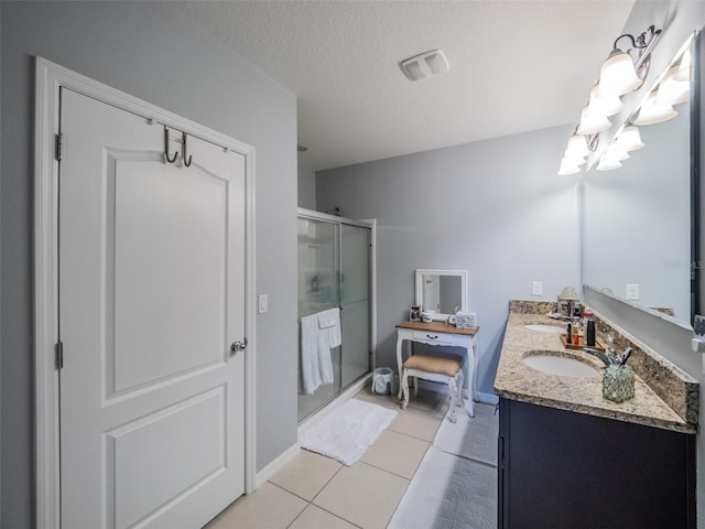 full bathroom with a textured ceiling, tile patterned flooring, a sink, double vanity, and a stall shower