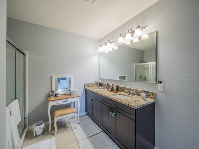 bathroom with double vanity, a stall shower, a sink, and tile patterned floors