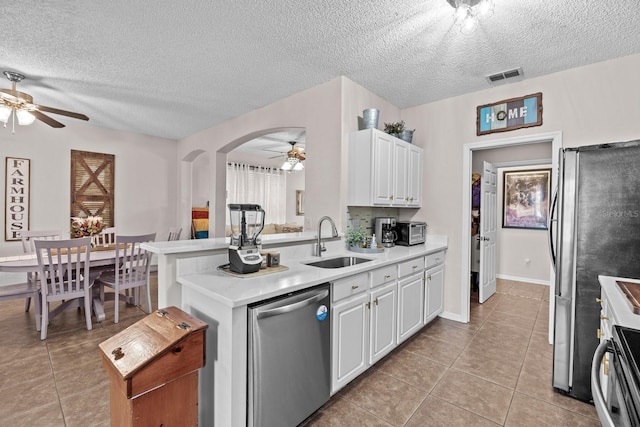 kitchen with a sink, a textured ceiling, a ceiling fan, appliances with stainless steel finishes, and light tile patterned floors