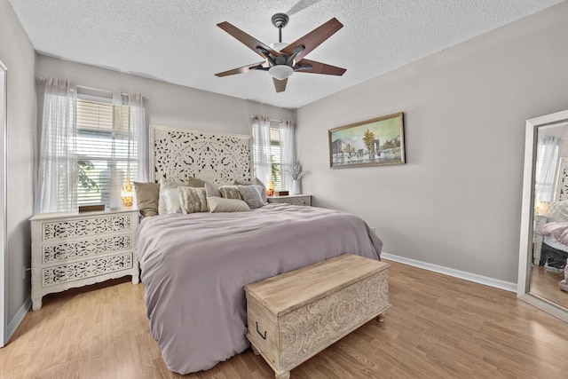 bedroom with baseboards, a textured ceiling, and light wood-style floors