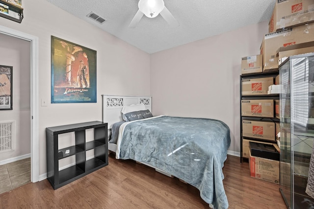 bedroom with a textured ceiling, wood finished floors, and visible vents