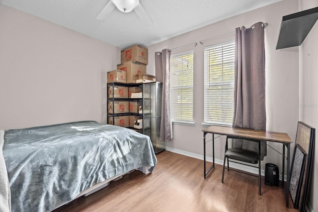 bedroom with wood finished floors, a ceiling fan, and baseboards