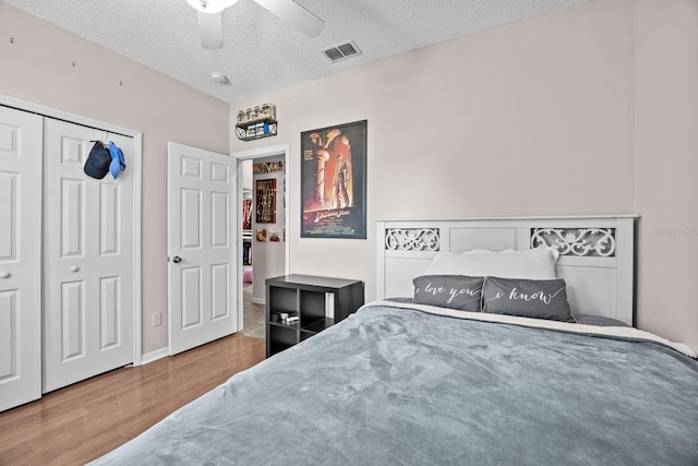 bedroom with ceiling fan, wood finished floors, visible vents, and a textured ceiling