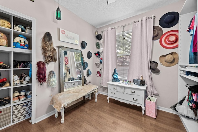 bedroom with wood finished floors, a textured ceiling, and baseboards
