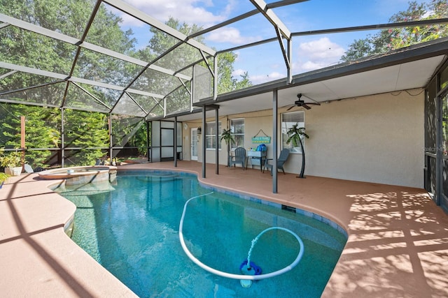 view of swimming pool with glass enclosure, a ceiling fan, a patio, and a pool with connected hot tub