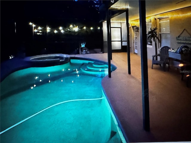 pool at twilight with a pool with connected hot tub and a patio
