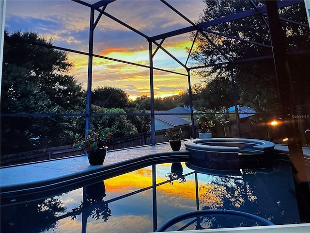 view of pool with fence, glass enclosure, and a pool with connected hot tub