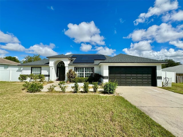 view of front facade with a garage, a front yard, and solar panels