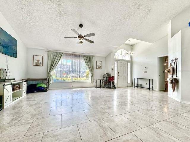 unfurnished living room featuring a textured ceiling, vaulted ceiling, ceiling fan, and light tile patterned flooring