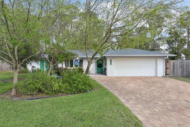 ranch-style house featuring a garage, fence, decorative driveway, and a front yard