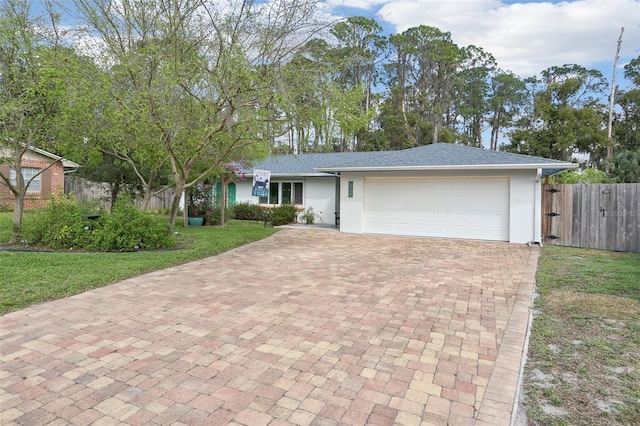 ranch-style home with an attached garage, fence, decorative driveway, stucco siding, and a front lawn