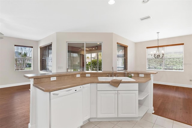 kitchen featuring pendant lighting, sink, dishwasher, white cabinetry, and light hardwood / wood-style floors