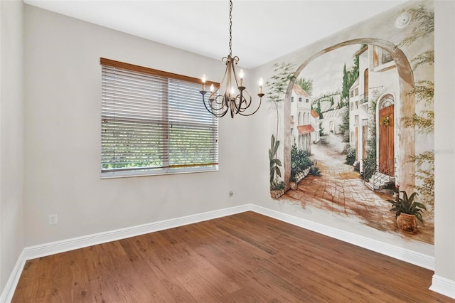 spare room with an inviting chandelier and hardwood / wood-style flooring