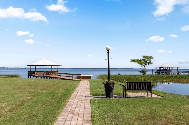 dock area with a water view, a lawn, and a gazebo