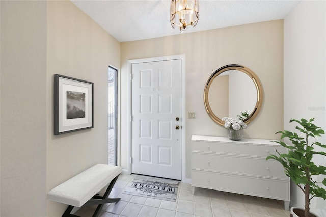 foyer entrance featuring a chandelier, light tile patterned floors, and a textured ceiling