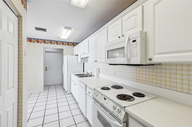 kitchen featuring light tile patterned floors, white appliances, a sink, visible vents, and white cabinetry