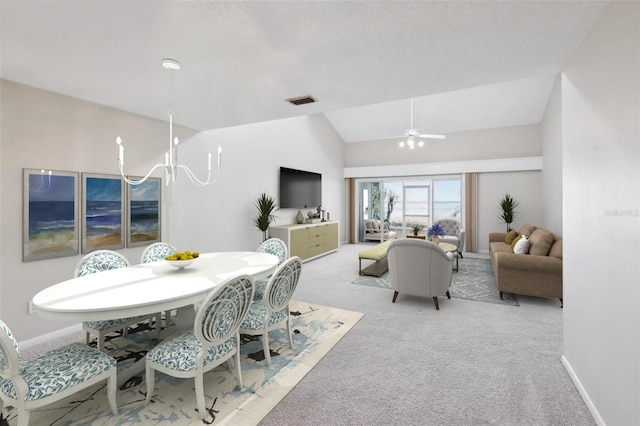 dining space featuring light carpet, ceiling fan with notable chandelier, visible vents, baseboards, and vaulted ceiling