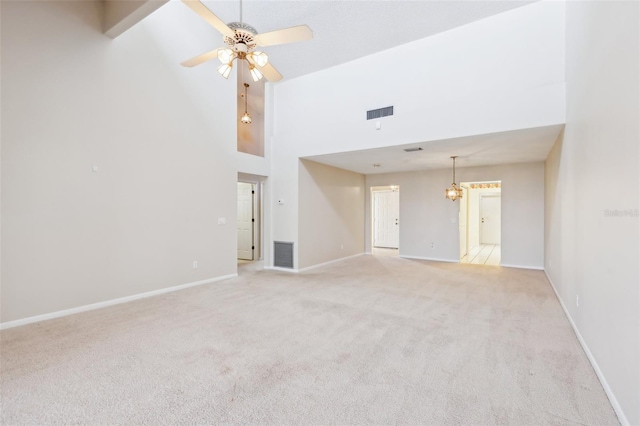 unfurnished living room featuring light carpet, ceiling fan with notable chandelier, a high ceiling, visible vents, and baseboards