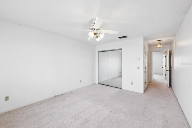 unfurnished bedroom featuring a ceiling fan, a closet, light colored carpet, and visible vents