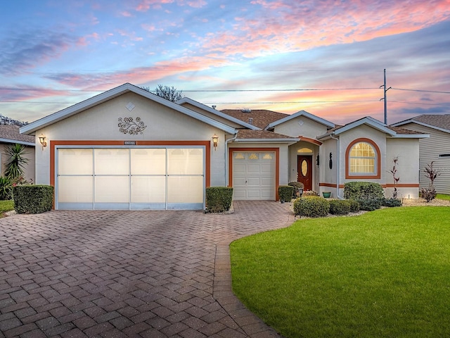 ranch-style house featuring a garage and a lawn