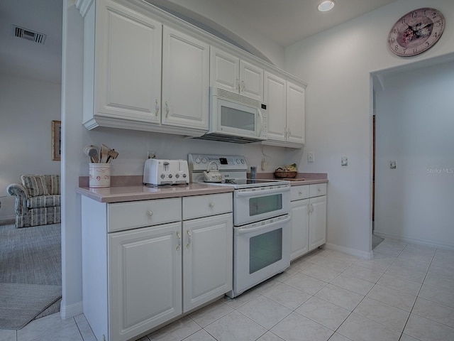 kitchen featuring white cabinetry, light tile patterned floors, and white appliances