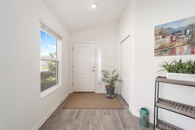 entryway with baseboards, vaulted ceiling, and light wood finished floors