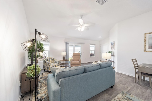 living area featuring baseboards, visible vents, a ceiling fan, lofted ceiling, and wood finished floors