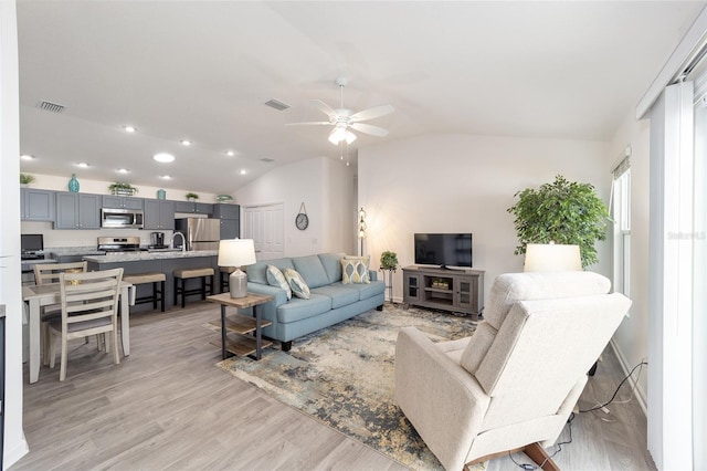 living area featuring visible vents, vaulted ceiling, light wood finished floors, and ceiling fan