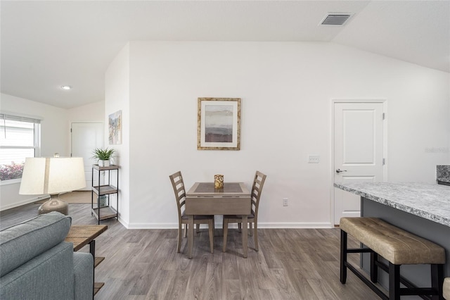 dining area featuring lofted ceiling, wood finished floors, visible vents, and baseboards