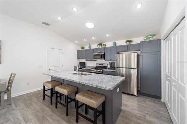 kitchen featuring visible vents, a kitchen island with sink, stainless steel appliances, gray cabinetry, and a sink