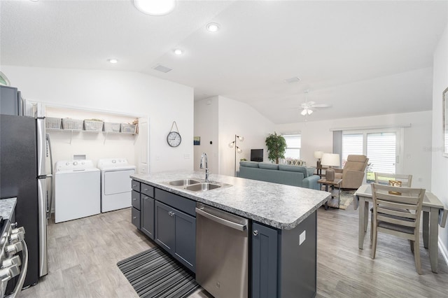 kitchen featuring light countertops, appliances with stainless steel finishes, a kitchen island with sink, a sink, and independent washer and dryer