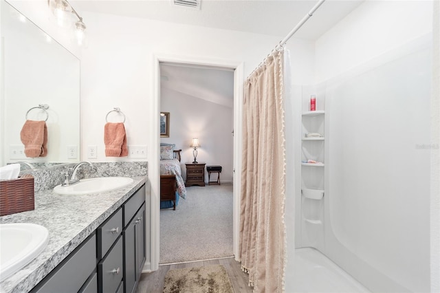 bathroom with double vanity, a shower with shower curtain, a sink, and ensuite bathroom