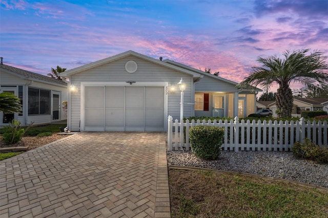 ranch-style house with a garage, decorative driveway, and a fenced front yard