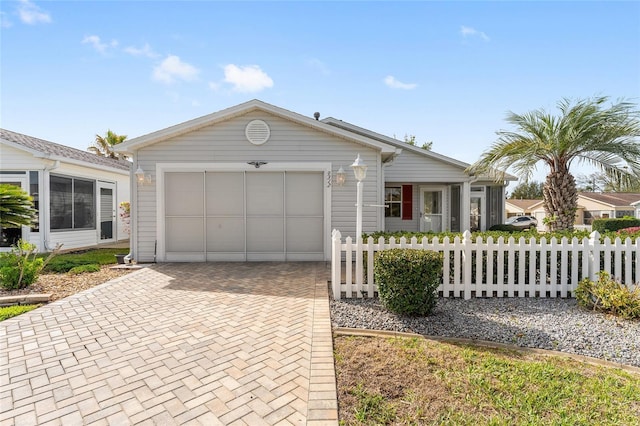 single story home with a garage, decorative driveway, and fence