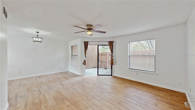 spare room with light wood-type flooring, baseboards, and ceiling fan with notable chandelier