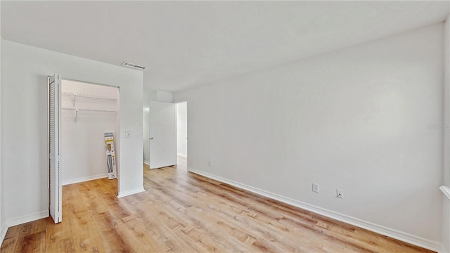 unfurnished bedroom with a closet, light wood-type flooring, visible vents, and baseboards