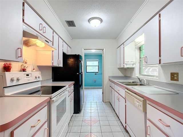 kitchen featuring light tile patterned flooring, white cabinetry, sink, white appliances, and a textured ceiling