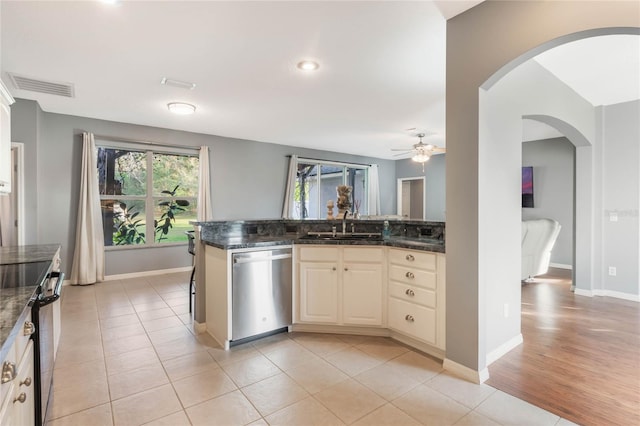 kitchen featuring sink, cream cabinets, stainless steel appliances, and dark stone counters