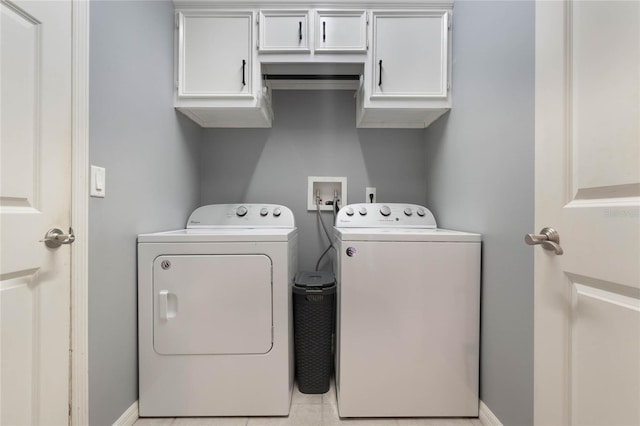 clothes washing area with light tile patterned floors, cabinets, and washing machine and clothes dryer