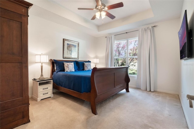 bedroom with light carpet, ceiling fan, and a tray ceiling