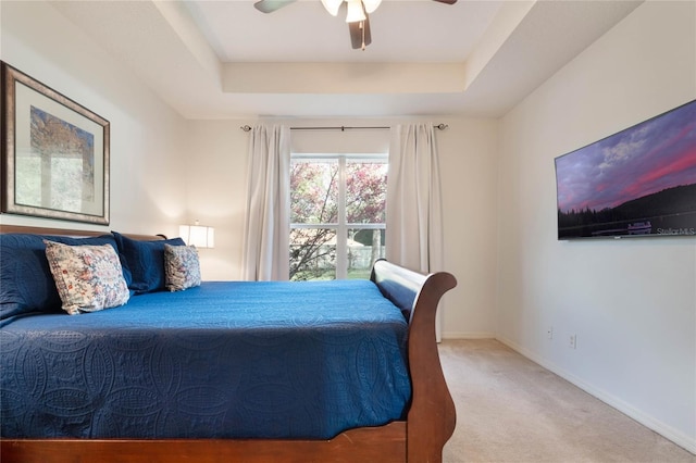 carpeted bedroom featuring ceiling fan and a tray ceiling