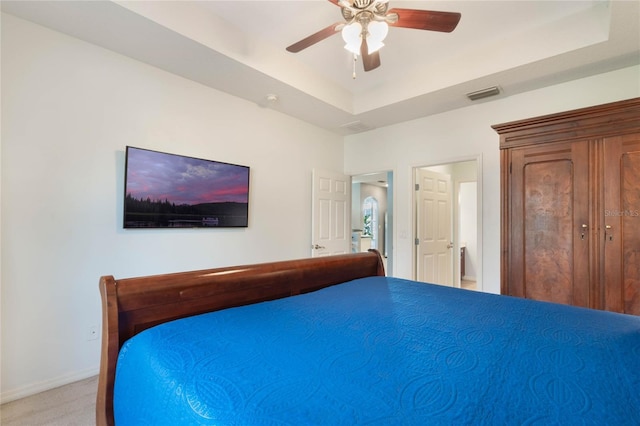 unfurnished bedroom featuring ceiling fan, light colored carpet, and a raised ceiling