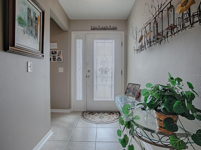 entryway with a textured wall, a textured ceiling, baseboards, and light tile patterned floors