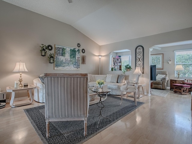 living room with light wood-type flooring, baseboards, and vaulted ceiling
