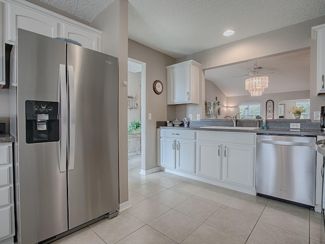 kitchen with light tile patterned flooring, stainless steel appliances, a sink, white cabinetry, and dark countertops