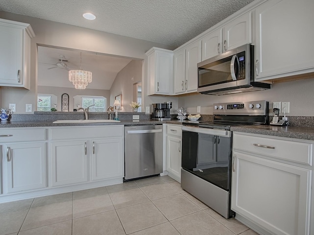 kitchen featuring dark countertops, white cabinetry, appliances with stainless steel finishes, and a sink