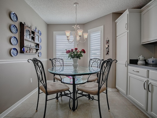 dining room featuring a textured ceiling, baseboards, a notable chandelier, and light tile patterned flooring